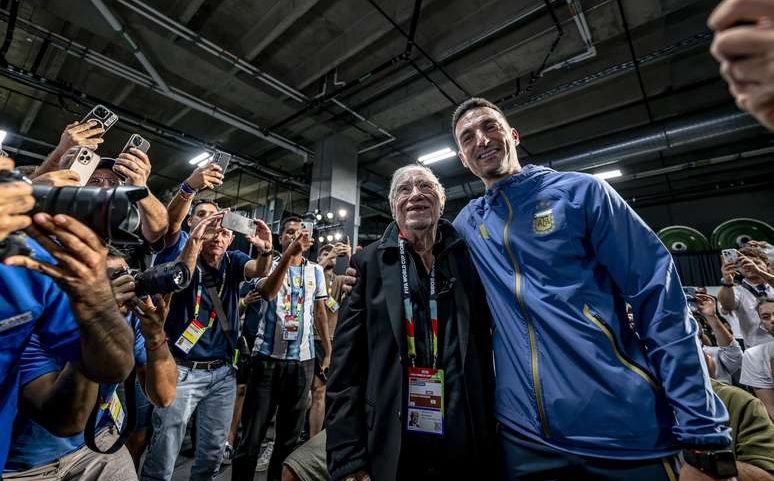 O jornalista esportivo argentino Enrique Macaya Márquez comparece à sua décima oitava Copa do Mundo aos 91 anos, ao lado do técnico da seleção argentina, Lionel Scaloni, durante uma coletiva de imprensa para a Argentina MD-1 no AT&T Stadium em 26 de junho de 2026, em Dallas, Estados Unidos.