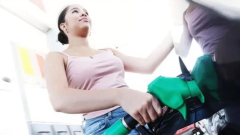 Getty Images A young woman fills her car at a petrol station