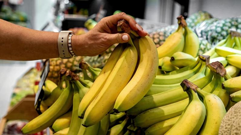 a woman buys fresh bananas at the supermarket