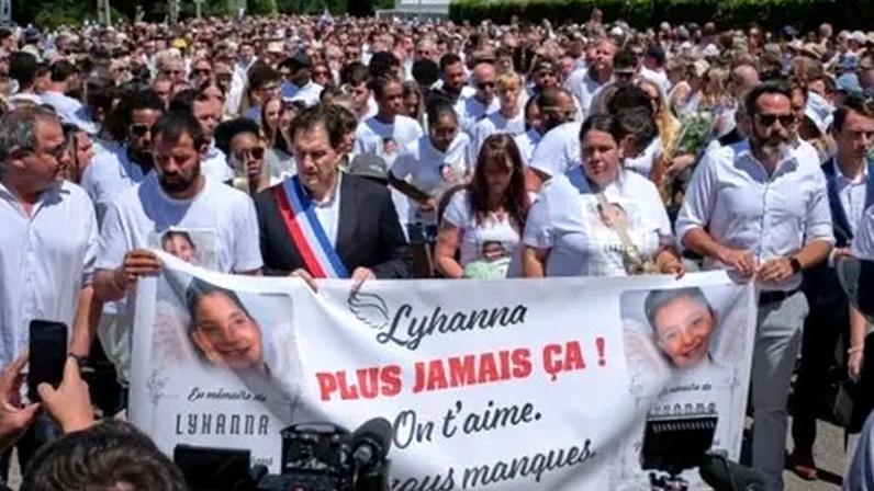EPA A crowd of people carry a banner reading 'never again' and featuring a picture of Lyhanna during a protest outside