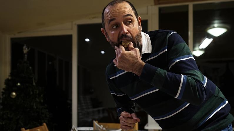 Foto colorida de homem pegando escondido o pedaço de alguma comida na ceia de natal - Metrópoles