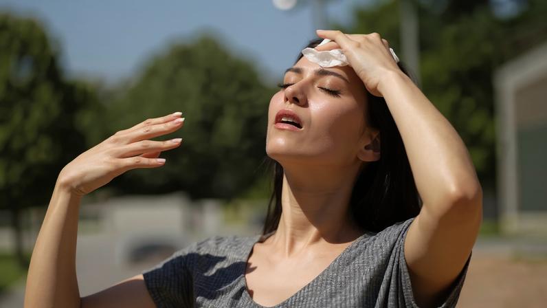 Mulher seca suor em dia de calor forte — Foto: Getty Images