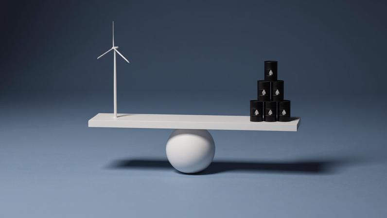 Transição energética: balança com turbina eólica de um lado e barris de petróleo do outro