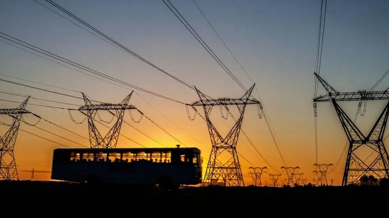 Ônibus com linhas de transmissão de energia ao fundo.