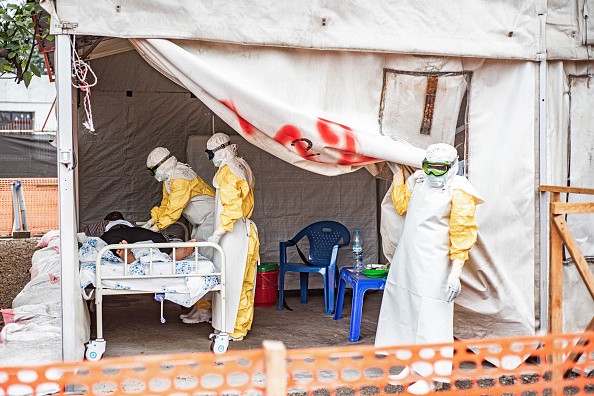 Trabalhadores usando equipamentos de proteção visitam um paciente em uma unidade de isolamento em um centro de tratamento de Ebola em Monigi, na República Democrática do Congo, em 2 de junho de 2026.