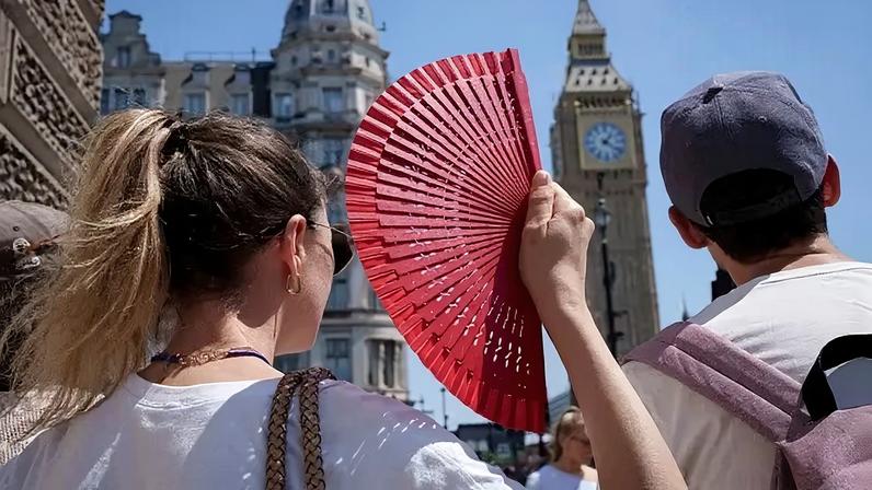 Uma turista se abana em Londres, na Inglaterra, durante a mais recente onda de calor, em 19 de junho de 2026.