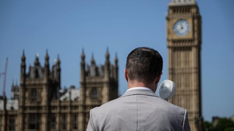 Homem usa um mini-ventilador portátil para se refrescar durante onda de calor em Londres.