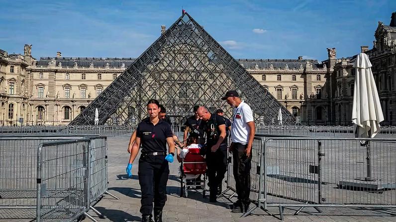 Bombeiros da Brigada de Incêndio de Paris escoltam uma pessoa para fora do Museu do Louvre durante a intensa onda de calor, em 25 de junho de 2026, em Paris, na França