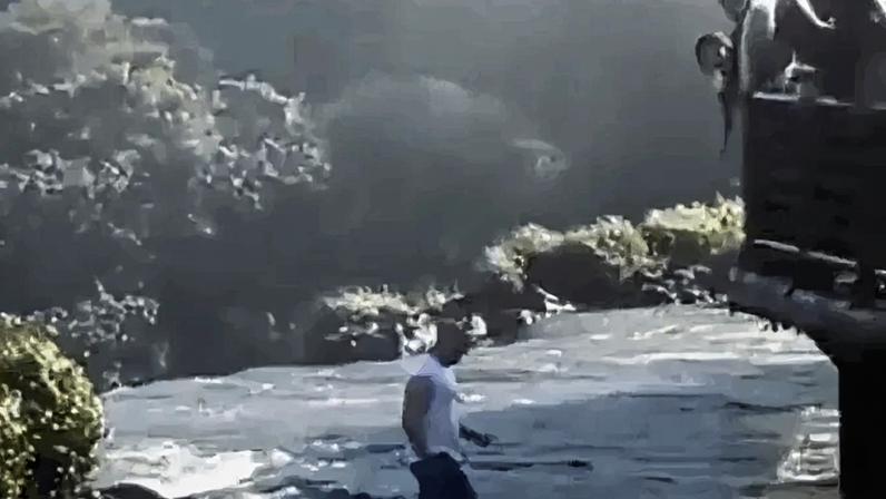 Homem pula nas águas, anda, procura o aparelho e volta para a ponte