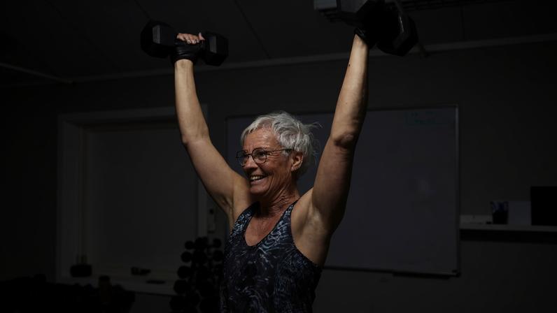 Foto colorida de mulher em estúdio de atividade física levantando halteres - Metrópoles