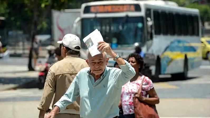 Idoso atravessando rua em dia de calor no Rio de Janeiro.