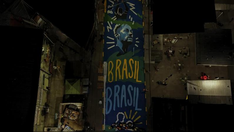 Imagem aérea da rua pintada na Penha com cores da seleção brasileira
