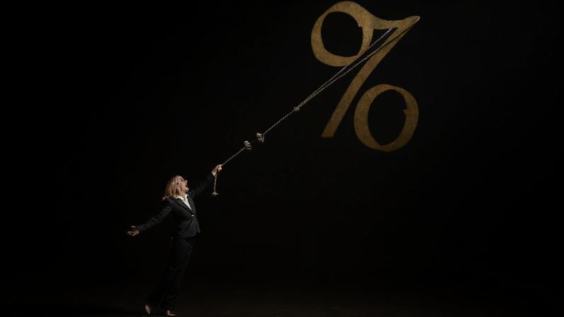 Ilustração traz uma mulher segurando uma corda amarrada a um sínbolo de porcentagem para ilustrar página de calculadora de juros compostos