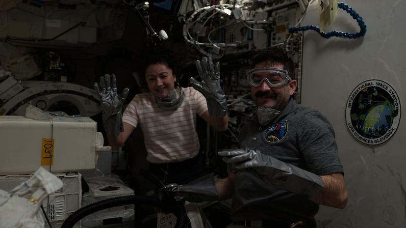 NASA astronauts Jessica Meir and Jack Hathaway, both Expedition 74 flight engineers, wear disposable gloves, dust masks, and safety goggles while unpacking temperature‑controlled scientific samples from a SpaceX Dragon cargo spacecraft and stowing them inside research facilities located aboard the International Space Station’s Kibo laboratory module.