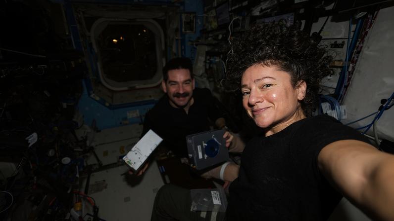 NASA astronauts Jack Hathaway and Jessica Meir, both Expedition 74 flight engineers, pose together as Hathaway shows off a pair of Advanced Space Experiment Sample Processor-4 research cassettes being used aboard the International Space Station to study how weightlessness affects drug crystals possibly leading to new pharmaceutical formulas.