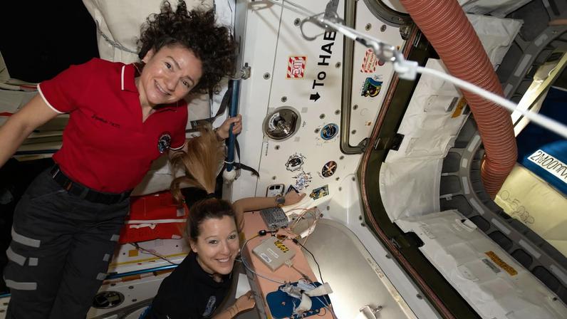Astronauts, from left, Jessica Meir and Sophie Adenot show off a Cygnus mission sticker for Northrop Grumman’s 24th cargo mission to the International Space Station.