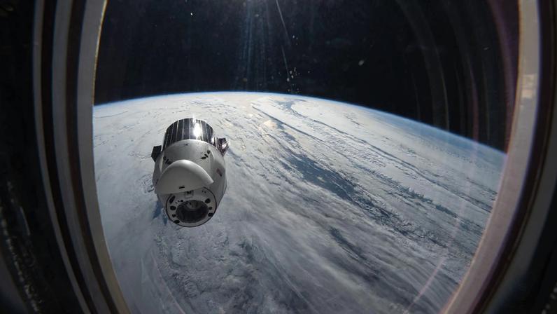 A SpaceX Dragon cargo spacecraft backs away from the International Space Station moments after undocking from the Harmony module's forward port while orbitng 265 miles above a cloudy North Pacific Ocean. Dragon, packed with completed science experiments and cargo for retrieval and analysis on Earth, parachuted to a splashdown off the coast of southern California the following day,