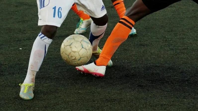 Na imagem, jogadores de futebol durante passe em partida