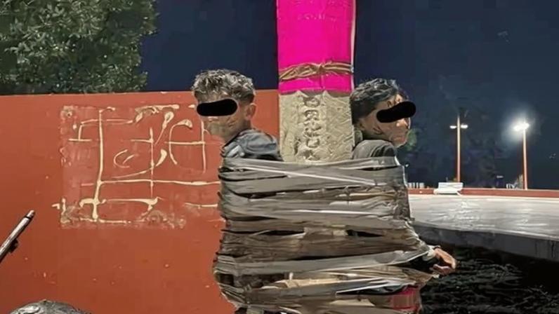 Imagem de suspeitos presos em poste com fita adesiva