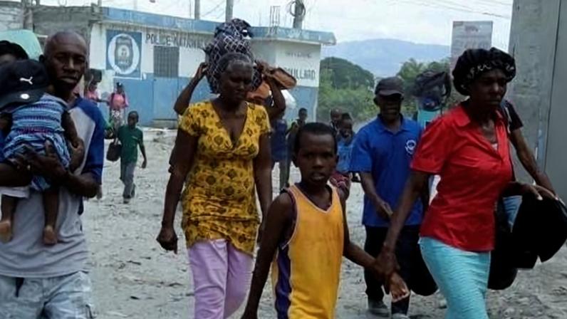 Moradores caminham por uma rua enquanto fogem de suas casas em Cité Soleil, após confrontos entre gangues rivais na capital do Haiti
