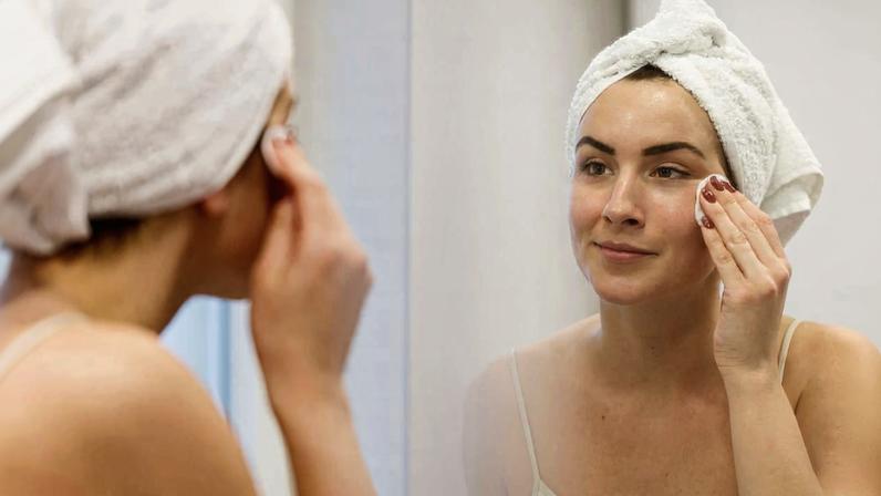 mulher aplicando produto de skincare na pele com algodão