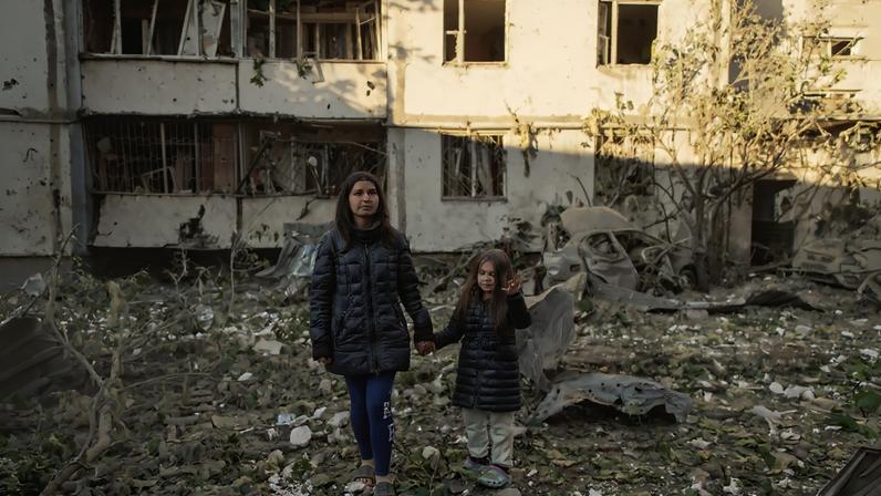 Mulher e filha perto do prédio residencial onde moram, que foi danificado durante os ataques de mísseis e drones russos contra Kiev