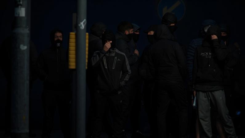 Jovens mascarados bloqueiam uma rua com destroços em chamas no norte de Belfast, Irlanda do Norte, na noite de 9 de junho de 2026.
