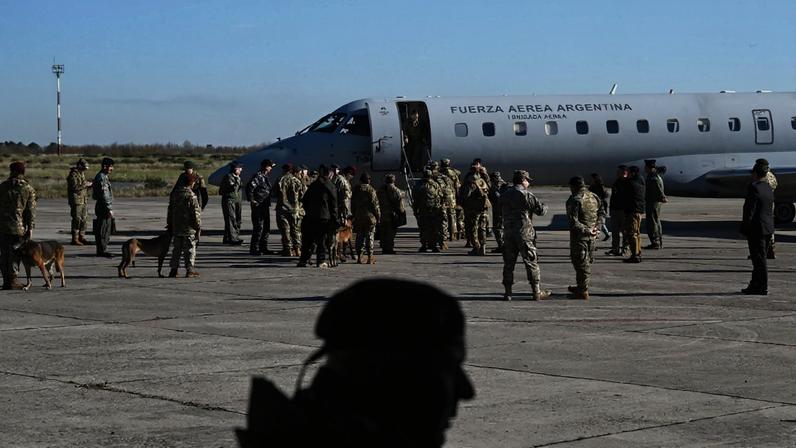 Equipes de resgate da Marinha argentina, acompanhadas de cães farejadores, embarcam em uma aeronave Embraer ERJ 140 da Força Aérea Argentina