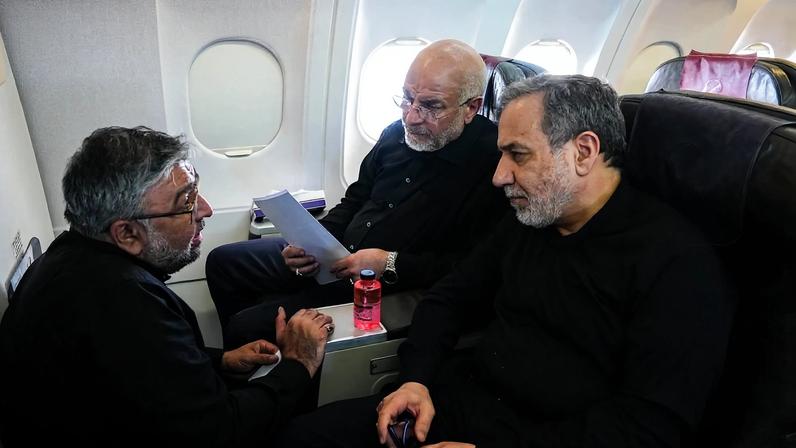 Presidente do Parlamento iraniano e chefe da equipe de negociação do Irã, Mohammad Bagher Ghalibaf (C), e o Ministro das Relações Exteriores iraniano, Abbas Araghchi (D), conversando com um membro da delegação iraniana durante voo