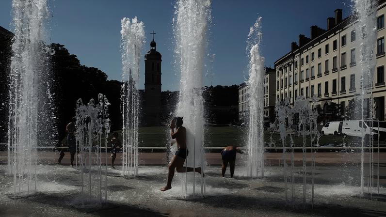 Crianças brincam enquanto se refrescam em uma fonte em Lyon, em 27 de maio de 2026, durante uma onda de calor que atingiu a França.