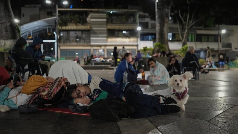 Uma mulher dorme ao lado de seu cachorro em uma praça após um terremoto em Caracas, em 25 de junho de 2026