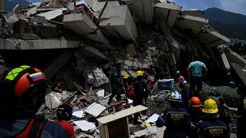 Bombeiros e equipes de resgate ao lado de um prédio que desabou após dois terremotos consecutivos em Los Corales, no estado de La Guaira