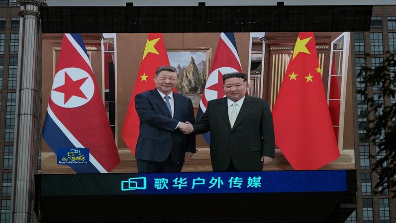 Telão gigante exibido do lado de fora de shopping em Pequim mostra programa de notícias sobre o encontro entre Xi Jinping e Kim Jong Un