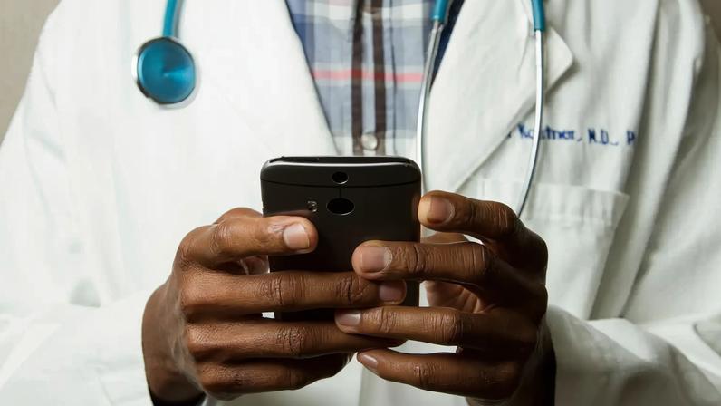 Médico com estetoscópio fala no celular. Foto: National Cancer Institute/Unsplash
