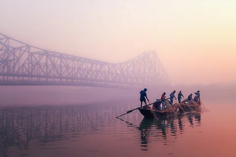 Fishermen pull in nets from a small boat at sunrise on the Hooghly River under Kolkata's Howrah Bridge (Credit: Marco Rutten/World Food Photography Awards)