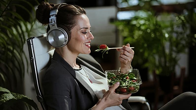 Getty Images Woman wearing headphones eats a salad (Credit: Getty Images)