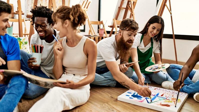 Foto colorida de um grupos de jovens adultos fazendo trabalhos artísticos