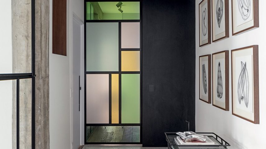 O corredor vira galeria e expõe a obra Estudo das Formas n. 4, de Nathalie Edenburg, sobre o bar Cart Rocca, do Estúdio Prole. Ao fundo, a porta inspirada na obra de Mondrian leva à suíte máster — Foto: André Mortatti/Divulgação | Projeto do escritório Zalc Arquitetura