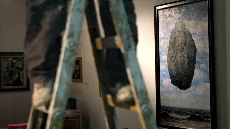 "The Castle of the Pyrenees" a painting by famous Belgian artist Rene Magritte is seen on a wall as a laborer on a ladder prepares the Israel Museum of Jerusalem for the re-opening after a three-year, $100 million renewal on July 20, 2010. AFP PHOTO/GALI TIBBON (Photo credit should read GALI TIBBON/AFP via Getty Images)