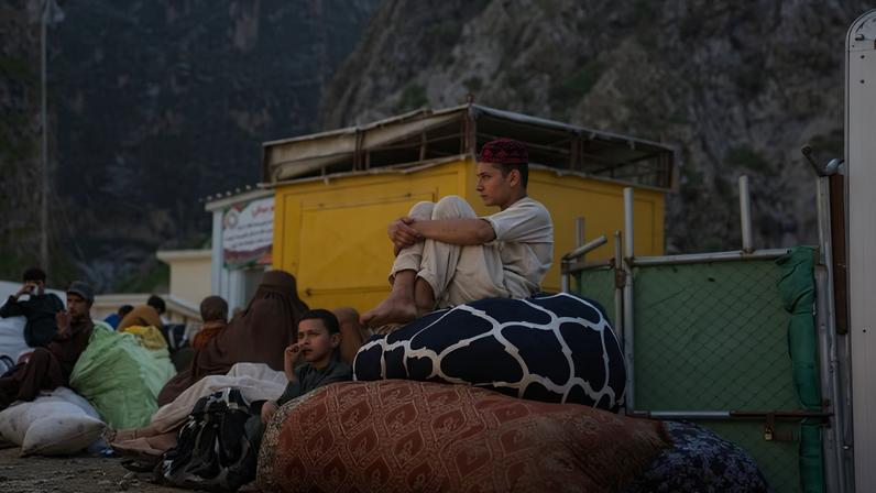 Jovens aguardam na fronteira de Torkham, entre o Paquistão e o Afeganistão, após retornarem com a família do território paquistanês