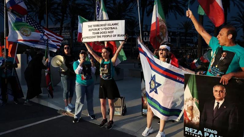 Um manifestante segura uma placa com os dizeres "A seleção de futebol da República Islâmica do Irã não representa o povo iraniano" em frente ao local de um treino da seleção iraniana.