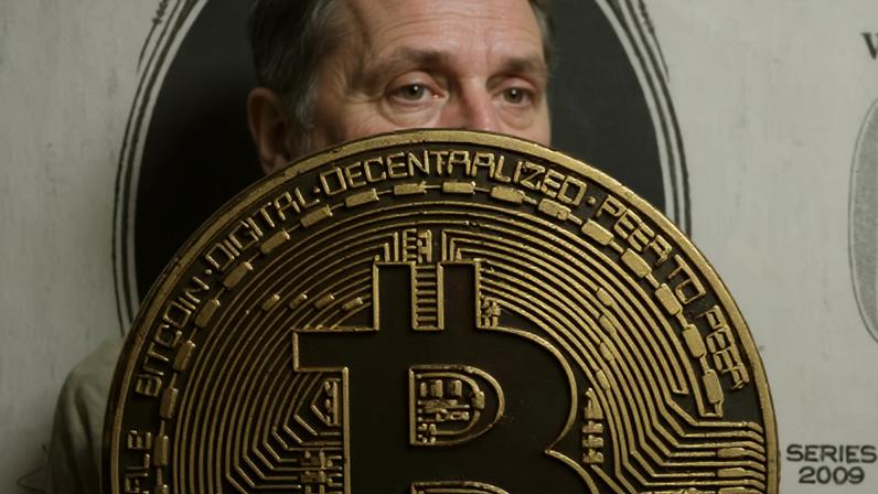 Representação do Bitcoin em cima de uma nota de dólar em foto de ilustração