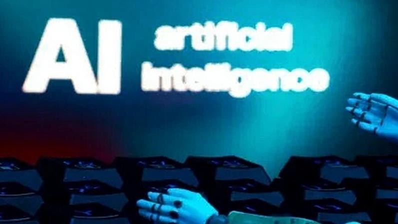 Foto ilustrativa mostra mensagem "IA inteligência artificial" e mãos de robô sobre um teclado