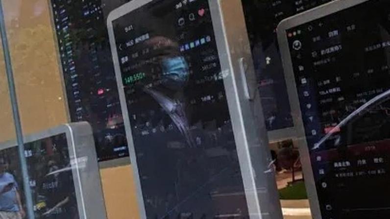Transeuntes passam por uma agência da Futu Securities que exibe um vídeo promocional mostrando as cotações das ações em Hong Kong