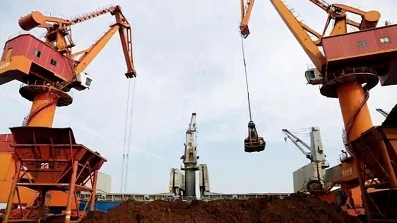 Guindastes descarregam minério de ferro importado de um navio de carga em um porto em Lianyungang, Jiangsu