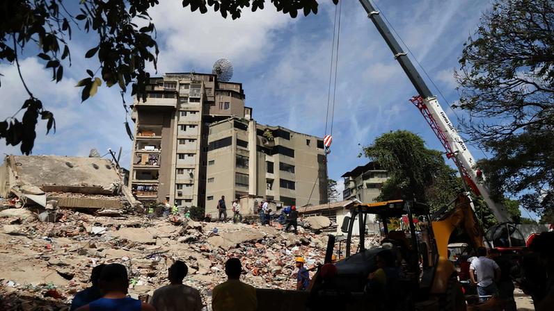 Pessoas e equipes de resgate trabalham nos escombros do edifício Moises, na Avenida Anauco, após um terremoto de magnitude 7,2 atingir a Venezuela