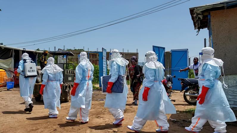 Pessoas reagem enquanto funcionários da Cruz Vermelha caminham em formação desinfetando o hospital geral de Rwampara antes de manusearem o corpo de uma pessoa que morreu de Ebola, em meio aos esforços das agências humanitárias para conter um novo surto da cepa Bundibugyo, em Rwampara, nos arredores de Bunia, província de Ituri, República Democrática do Congo, em maio — Foto: Reuters