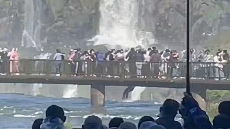 Imagem colorida mostra turista descendo de ponto nas Cataratas do Iguaçu para pegar telefone que havia caido - Metrópoles