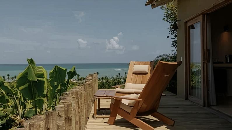 Varanda privativa de uma das suítes da Vila Figo, hotel boutique no Quadrado rodeado por vegetação e com vistas para o mar