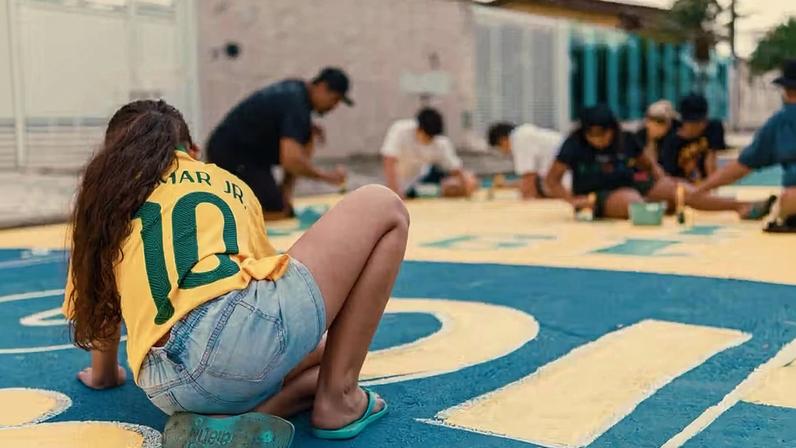 Moradores se reúnem na Praia Grande, no litoral paulista, para pintar ruas e resgatar uma das tradições mais simbólicas das Copas do Mundo no Brasil